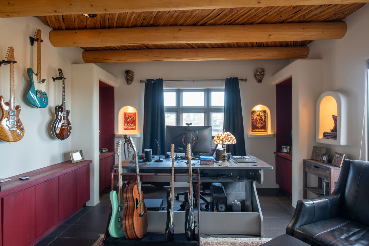 The home studio room stands out, brimming with vintage guitars. Leather accent chairs offer a comfortable listening spot, all under the rustic charm of wooden beams.
