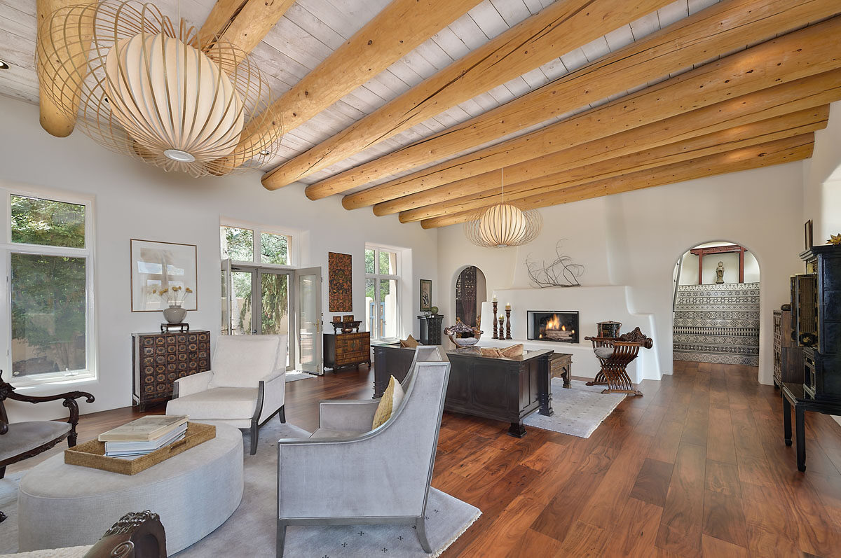 With gleaming acacia wood floors and rustic wooden beams, the living room exudes luxury and coziness, complemented by plush accent chairs and bamboo rattan pendant lights.