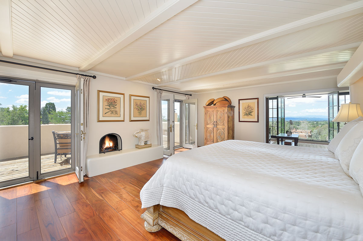The spacious master suite offers a resort-like feel with French doors highlighting a barrel-vault, cove-lit ceiling, expansive windows, and a plush white bed.