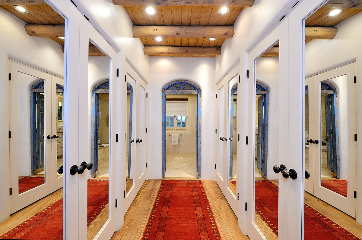 A sleek hallway features white doors, a red carpet, and soft neutral lighting.