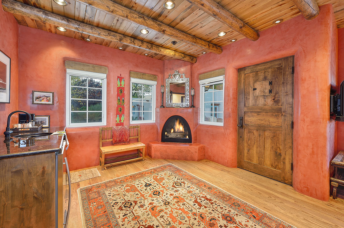 The master bedroom and bathroom renovation, featuring a red southwestern theme, includes wood furniture, a vibrant carpet, and a cozy fireplace. The continuity of the theme is maintained with wood floors and ceilings, enhancing the rustic charm.