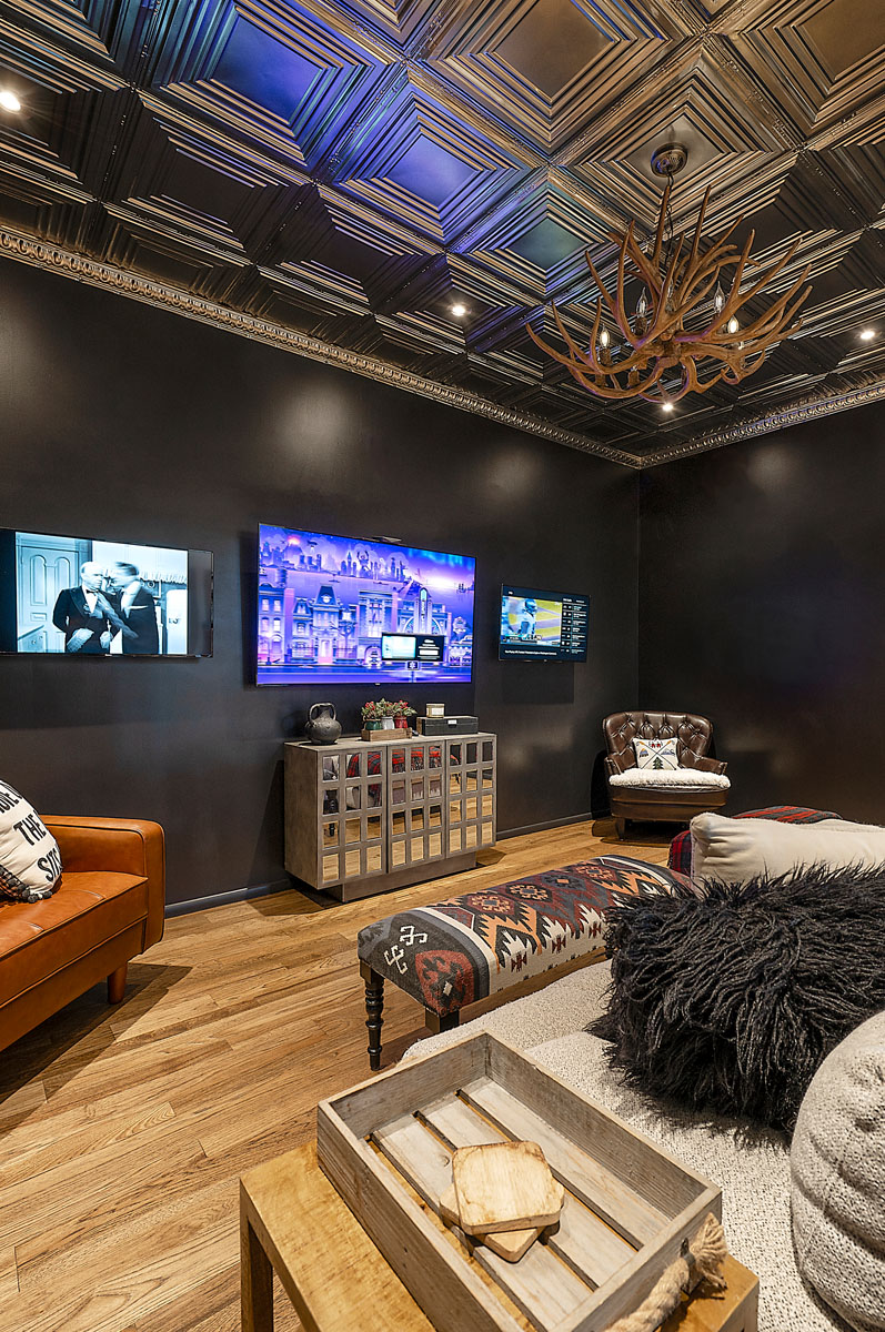 Chic media room in a Santa Fe home featuring a decorative ceiling, dark walls, multiple screens, and cozy seating arrangements, ideal for movie nights.
