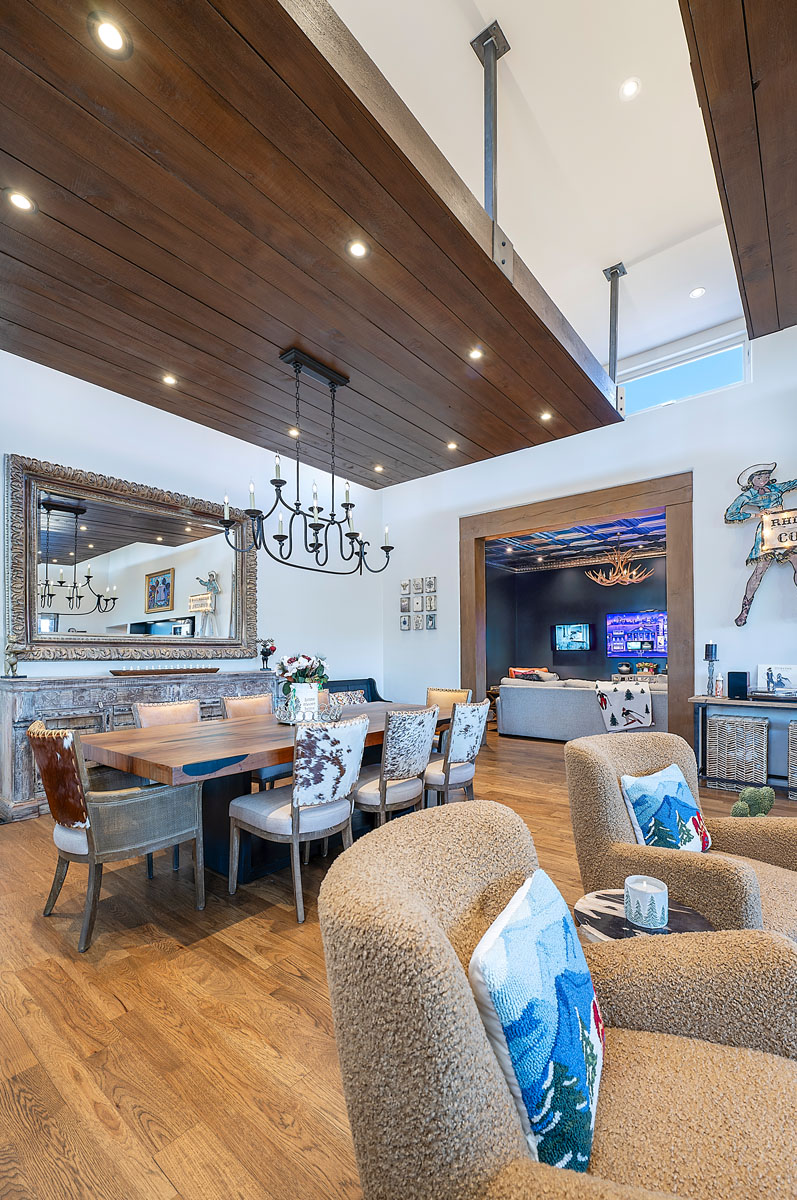Elegant and welcoming interior of a Santa Fe home featuring a wooden ceiling, cozy sitting area, and a dining space leading into a media room with vibrant decor.