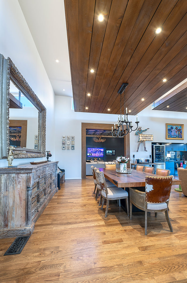 Spacious and inviting dining area in a Santa Fe home, highlighted by a rustic wood ceiling, hardwood floors, and an open layout leading to a modern kitchen.