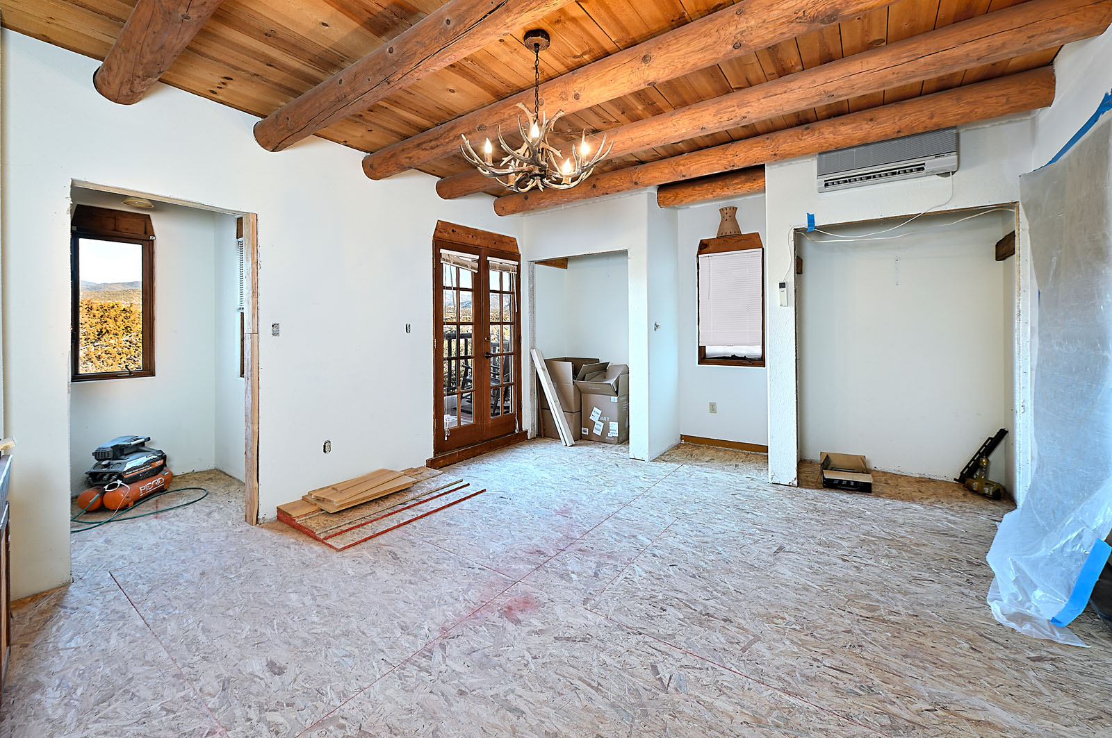 Renovation in progress of a historic Santa Fe home by Fabuwallous Solutions, featuring exposed wooden beams and plaster walls.