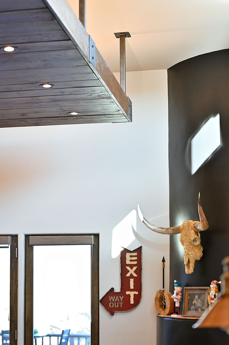 Eclectic corner of a Santa Fe home with a dark accent wall featuring a mounted longhorn skull, complemented by wooden ceiling beams and vintage decor elements.