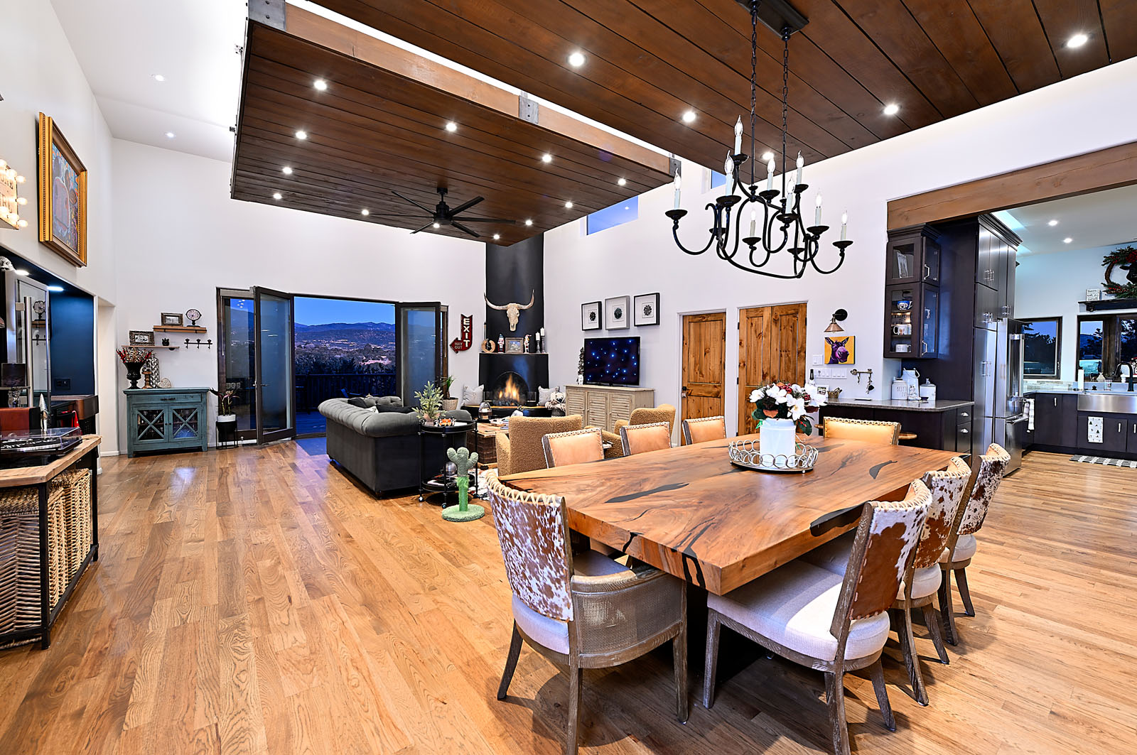 Spacious and elegantly designed living space in a Santa Fe home featuring wooden ceilings, a large dining table, and an open plan that connects to the kitchen and lounge areas.