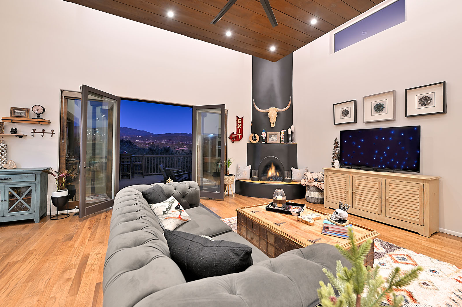 Inviting and stylish living room with a plush sectional sofa, modern fireplace, and expansive glass doors that open to stunning mountain views in a Santa Fe home.