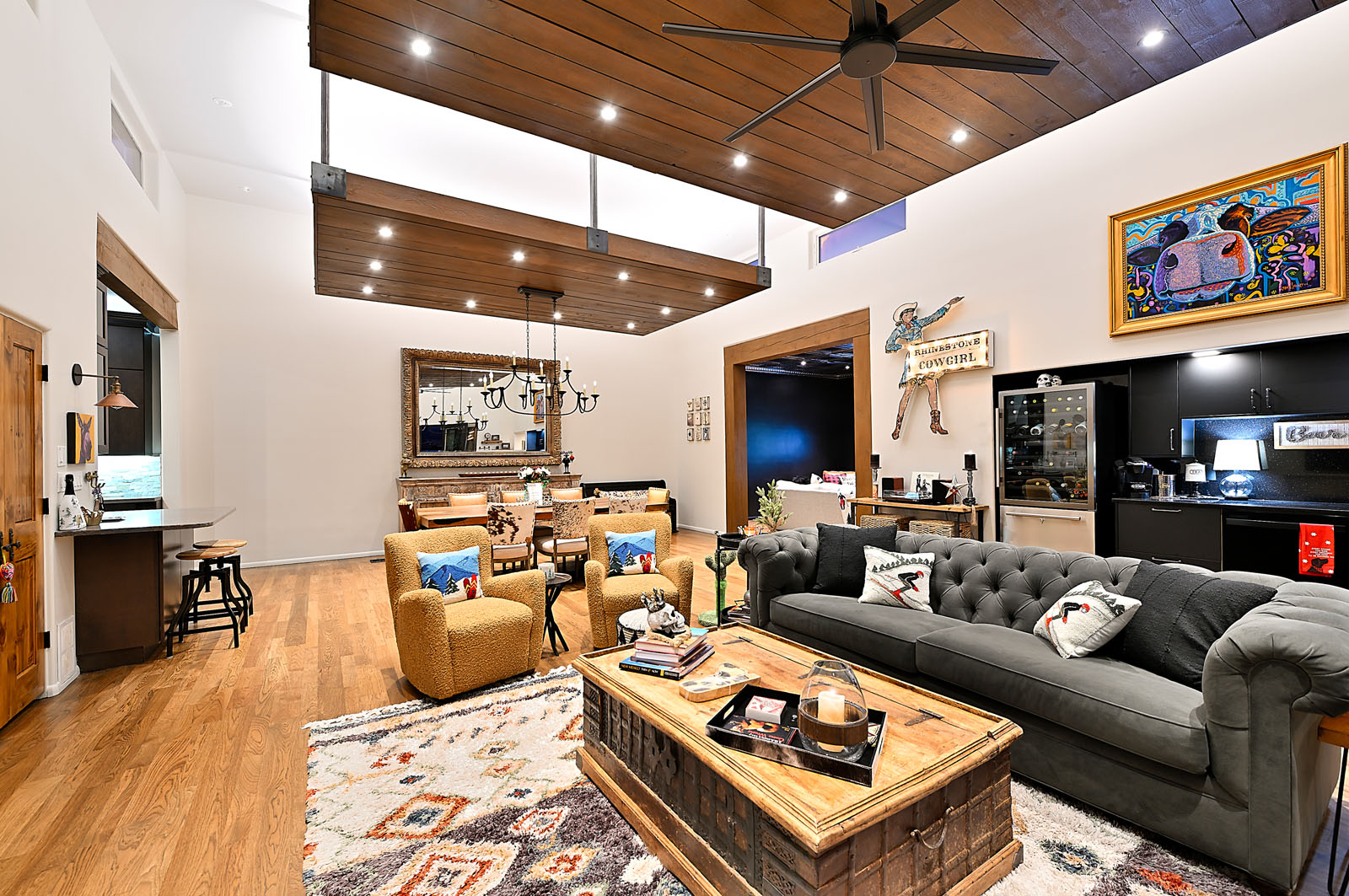 Modern and cozy living area in a Santa Fe home, featuring a mix of elegant sofas, vibrant rugs, wooden ceilings, and an open layout connecting to the kitchen.